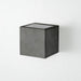 Wall light in 10cm cubic shape made from dark grey concrete with a silver coloured inside plating